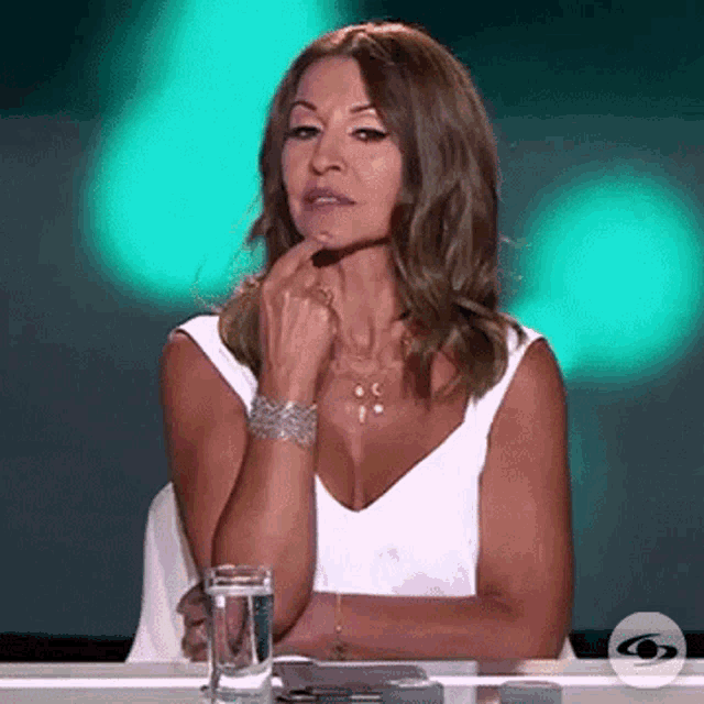 a woman is sitting at a table with a glass of water and a ring on her finger .