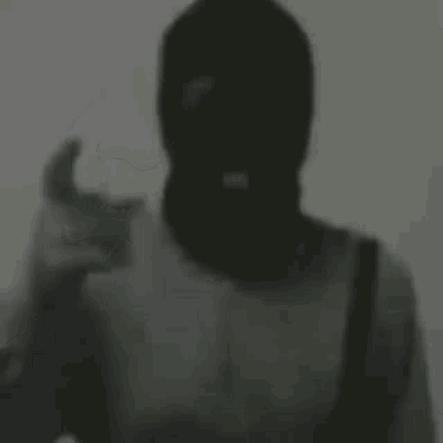 a man in a ski mask is giving a thumbs up sign .