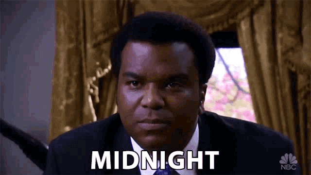 a man in a suit and tie is saying " midnight "