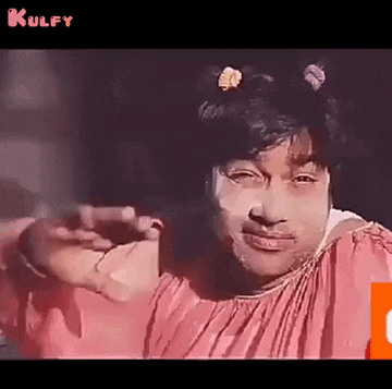 a man in a pink dress is making a funny face while pointing at the camera .