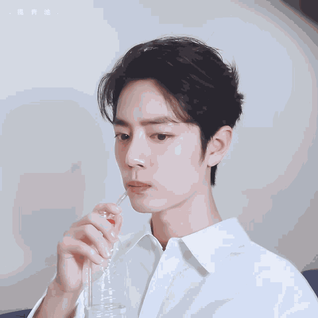 a man in a white shirt is drinking from a plastic bottle