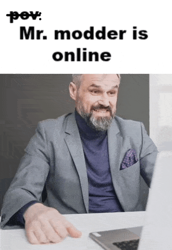 a man with a beard is sitting at a desk in front of a laptop computer with the caption " mr. modder is online "