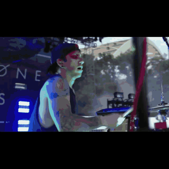 a man is playing drums in front of a sign that says ' one ' on it