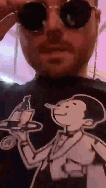 a man wearing sunglasses and a shirt with a cartoon man holding a tray .