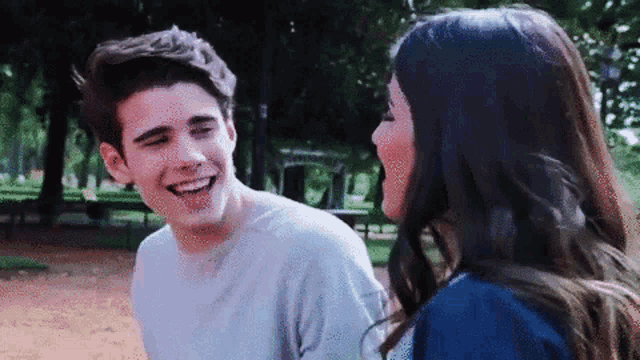 a man and a woman are looking at each other and smiling .