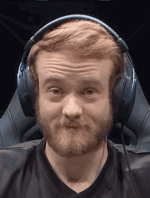 a man with a beard wearing headphones making a face
