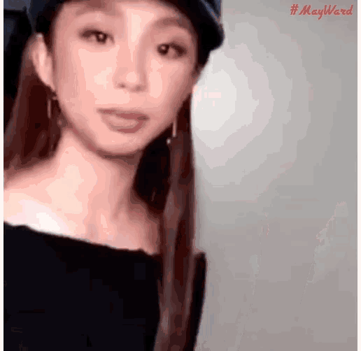 a woman wearing a hat and earrings is looking at the camera