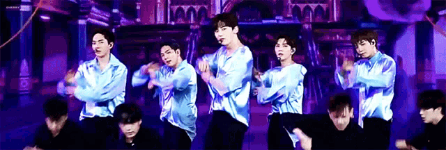 a group of men are dancing on a stage in front of a purple background