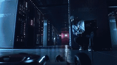 a person is standing in a dark room with a lot of servers and a red light .