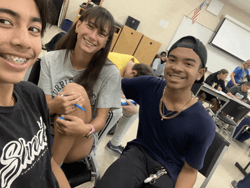 a boy wearing a black shirt with the word squad on it sits in a classroom