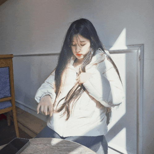 a woman with long hair is sitting at a table with a cell phone