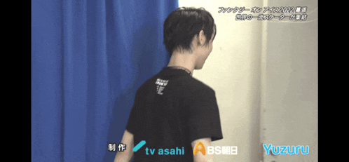 a man stands in front of a blue curtain with tv asahi written on the bottom right
