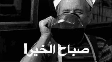 a man is drinking a cup of coffee from a glass .
