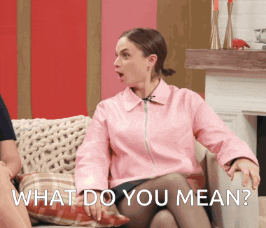 a woman in a pink jacket is sitting on a couch with the words " what do you mean " below her