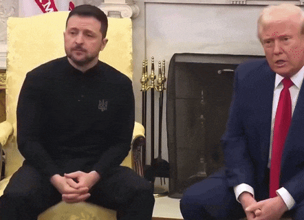 a man in a black shirt with the letter m on it sits next to donald trump