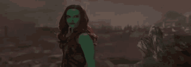 a woman in a green dress is standing next to a giant monster .
