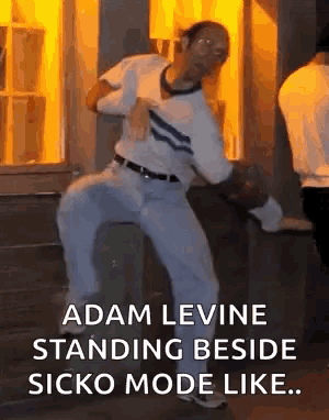 a man is dancing in front of a building with the words adam levine standing beside sicko mode like .