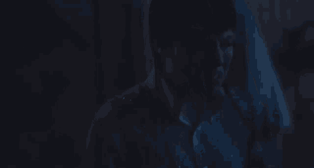 a man is screaming in the dark while holding a cell phone in his hand .