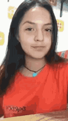 a woman in a red shirt is taking a selfie with her phone .