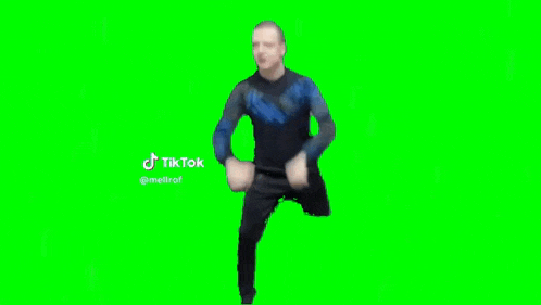 a man in a blue shirt and black pants is dancing in front of a green screen .