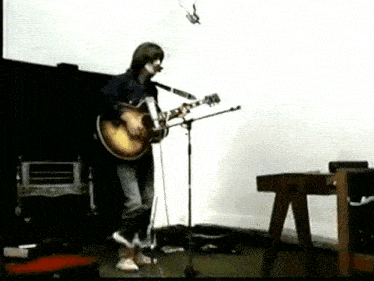 a man is playing an acoustic guitar in front of a microphone