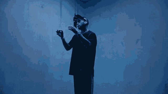 a man in a black shirt stands in a dark room