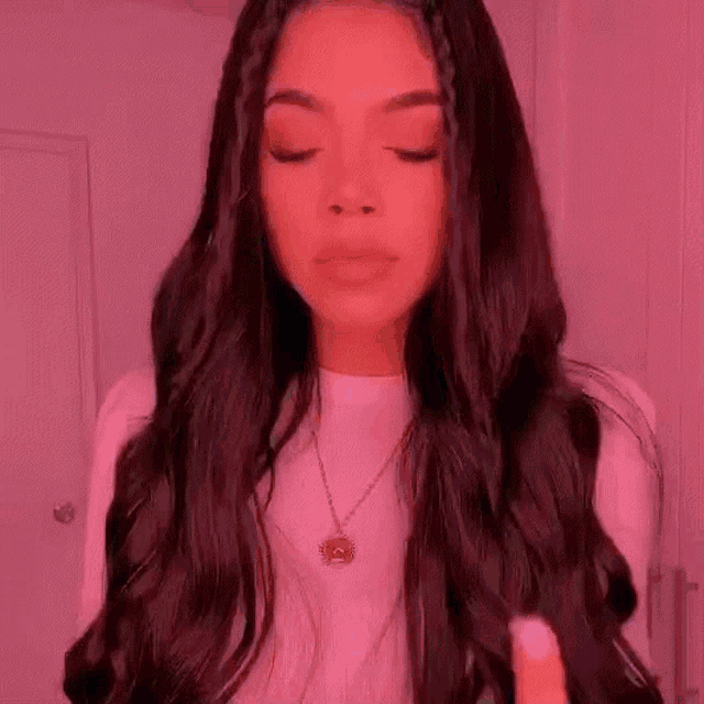 a woman with long black hair wearing a white shirt and a necklace