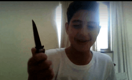 a young boy in a white shirt is holding a knife in front of his face