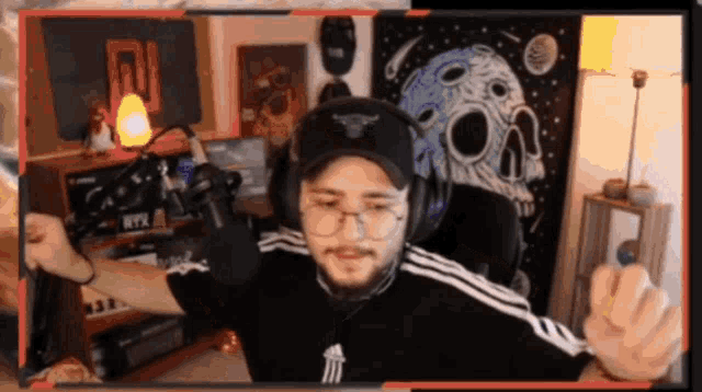a man wearing headphones and a hat is sitting in front of a microphone ..