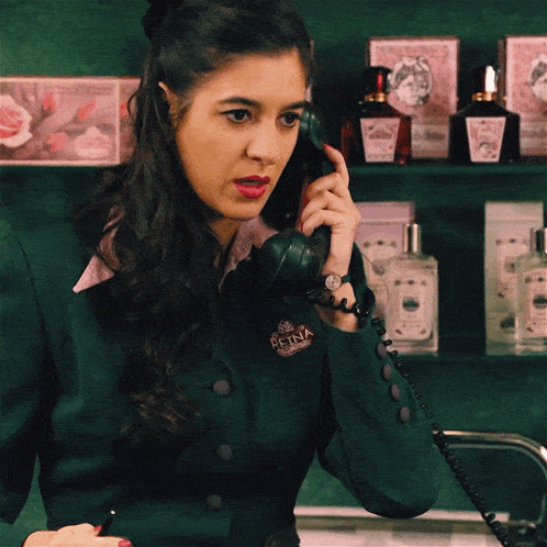 a woman talking on a phone with a penna badge on her green jacket
