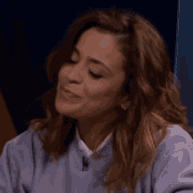 a close up of a woman wearing a purple sweater and a white shirt .