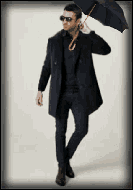 a man in a black coat and sunglasses holds an umbrella