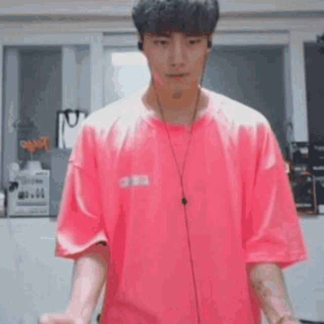 a man wearing headphones and a pink shirt is standing in a room .