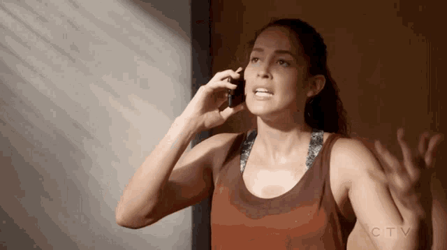 a woman in a tank top is talking on a cell phone
