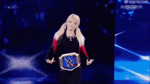a woman is standing on a stage holding a wrestling belt with the letter w on it .