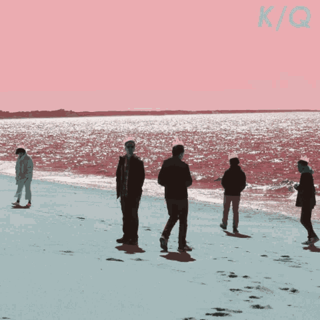 a group of people standing on a beach with k / q written on the bottom right
