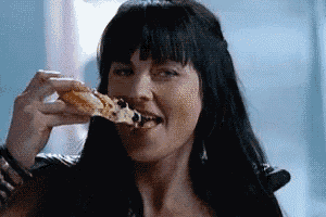 a woman is eating a slice of pizza with her mouth open