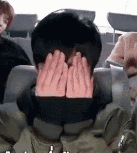 a man is covering his face with his hands while sitting in a car .