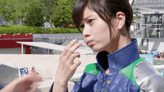 a woman in a blue and green jacket holds a sign that says fuji on it