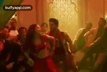 a woman in a red dress is dancing in a crowd of people .