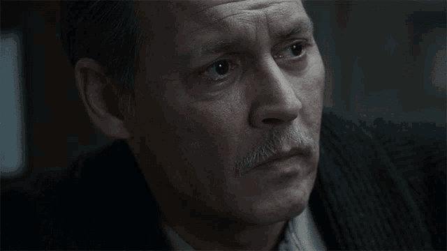 a close up of a man with a mustache looking down