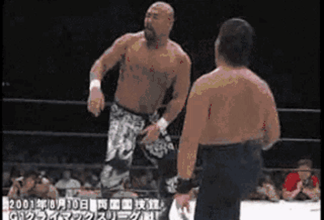two men are wrestling in a ring with chinese writing on the bottom