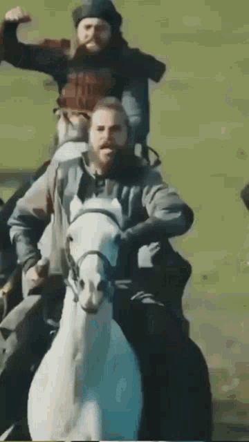 a man with a beard is riding a white horse