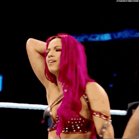 a woman with pink hair is in a wrestling ring with a referee
