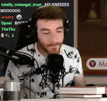 a man wearing headphones is sitting in front of a microphone with the words totally_notangel_trust on the screen
