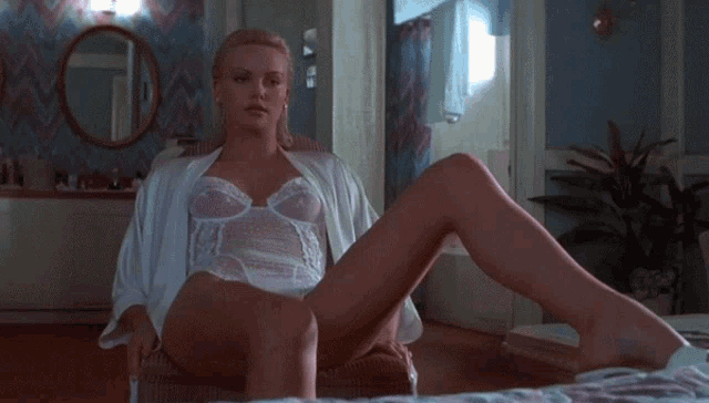 a woman in white lingerie sits on a bed with her legs crossed