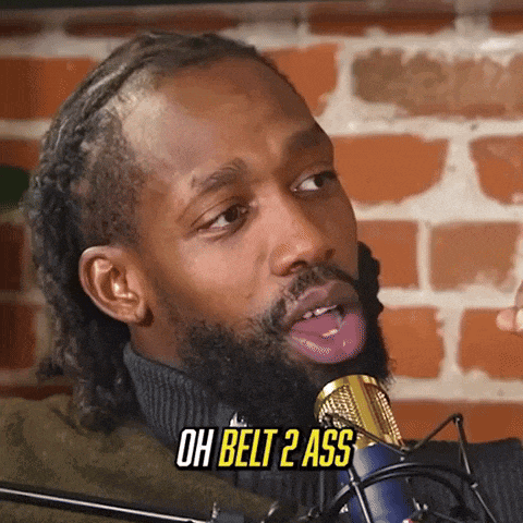 a man with a beard is sticking his tongue out in front of a microphone and says oh belt 2 ass .