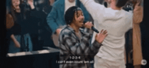 a man is singing into a microphone in front of a crowd of people .