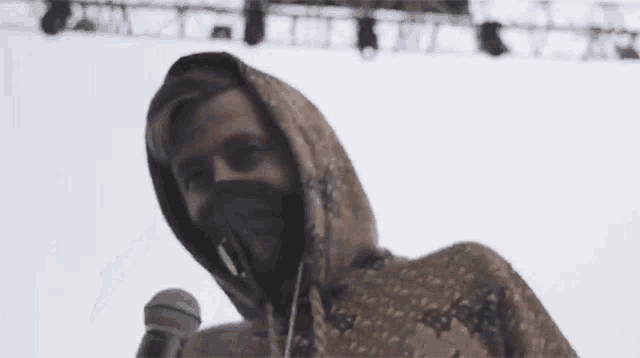 a man in a hoodie is holding a microphone in front of a stage .