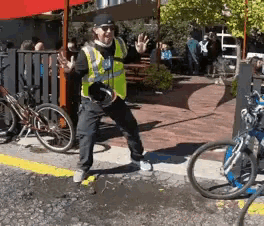 a man wearing a safety vest stands in front of a bike